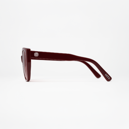 Vista lateral do óculos de sol vermelho cereja modelo Hooker’s Lips da Use Let’s Brasil, com detalhe metálico na haste, lentes vermelhas em degradê e logo Let’s na ponta da haste, sobre fundo branco neutro